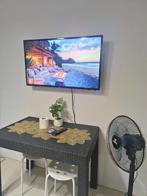 a table with a fan and a television on a wall at SEA RESIDENCES NEAR MALL OF ASIA BY Amigo's place in Manila