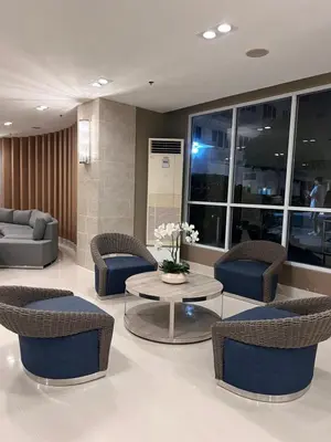 a lobby with chairs and a table in a building at Sea Residences MOA Manila By Paul XIVI in Manila
