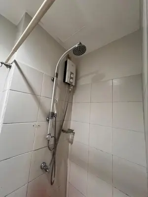 a shower with a shower head in a bathroom at Sea Residences MOA Manila By Paul XIVI in Manila
