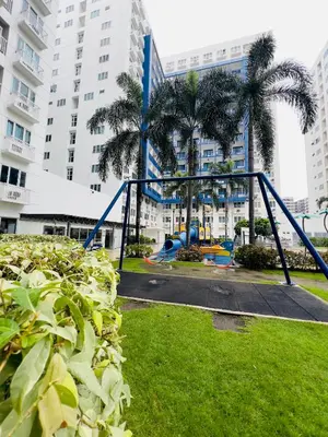 a playground in a park with palm trees and buildings at Sea Residences MOA Manila By Paul XIVI in Manila