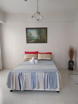 a bed in a white room with at Emy Cozy Studio unit with street view balcony in Manila