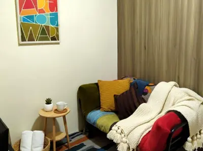 a living room with a couch with a blanket on it at Ortigas CBD Greenfield Residences in Manila
