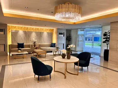 a lobby with chairs and tables and a chandelier at Ortigas CBD Greenfield Residences in Manila
