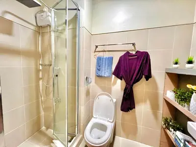 a bathroom with a toilet and a glass shower at Ortigas CBD Greenfield Residences in Manila