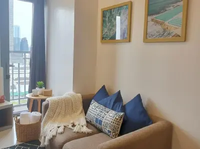 a living room with a brown couch with blue pillows at Ortigas CBD Greenfield Residences in Manila