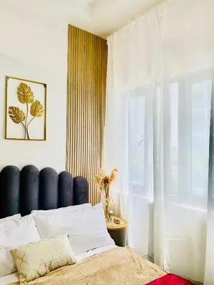 a bedroom with a bed with a blue headboard and a window at MOA SHORE - Exxy SUITES in Manila