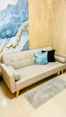a tan couch in a room with a painting at MOA SHORE - Exxy SUITES in Manila