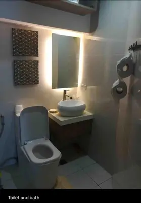 a bathroom with a toilet and a sink and a mirror at Fort Victoria Condominium Tower C in Manila