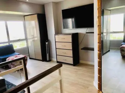 a living room with a tv and a dresser with a large mirror at Fort Victoria Condominium Tower C in Manila