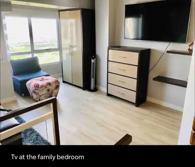 a living room with a flat screen tv and a chair at Fort Victoria Condominium Tower C in Manila
