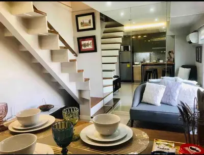 a living room with a staircase and a table with dishes on it at Fort Victoria Condominium Tower C in Manila