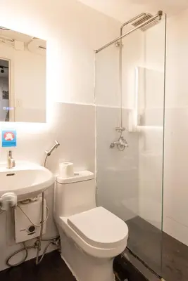a bathroom with a toilet and a sink and a shower at Homey and Cozey Poblacion Makati S04 in Manila