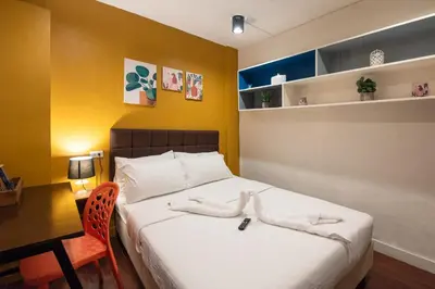 a bedroom with a bed with a desk and a chair at Homey and Cozey Poblacion Makati S06 in Manila
