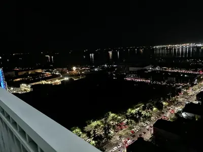 a view of a city at night from a balcony at Cozy Urban Apartment in Pasay City in Manila