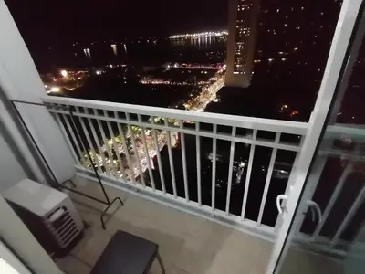 a balcony with a view of a city at night at Cozy Urban Apartment in Pasay City in Manila