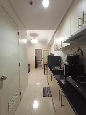 a kitchen with white cabinets and black counter tops at Sea Residences Staycation MOA Pasay in Manila