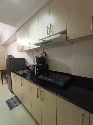 a kitchen with white cabinets and a black counter top at Sea Residences Staycation MOA Pasay in Manila