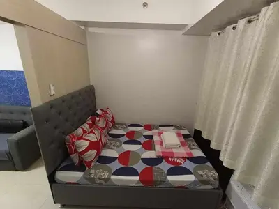 a small bedroom with a bed with a patterned blanket at Sea Residences Staycation MOA Pasay in Manila
