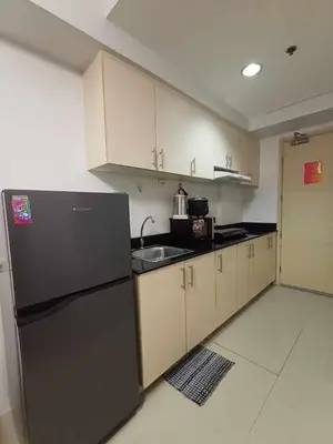 a kitchen with a black refrigerator and a sink at Sea Residences Staycation MOA Pasay in Manila