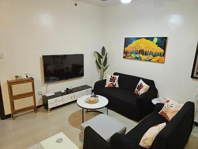 a living room with two couches and a flat screen tv at Marty's Turf at San Lorenzo in Manila