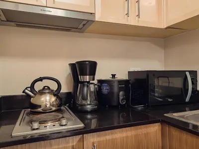 a kitchen counter with a tea kettle and a microwave at One Palm Tree Condominium in Manila