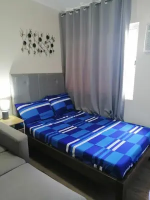 a blue bed in a room with a curtain at Homey Staycation in Silang Cavite! Fullerton Suites Puting Kahoy - near CKS, AUP, PNPA, in Puting Kahoy