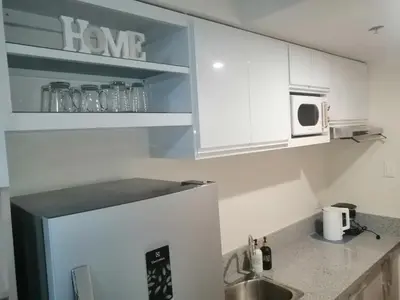 a kitchen with white cabinets and a sink and a microwave at Homey Staycation in Silang Cavite! Fullerton Suites Puting Kahoy - near CKS, AUP, PNPA, in Puting Kahoy