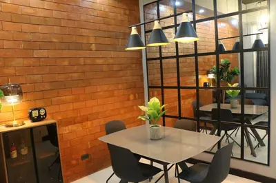 a dining room with a table and chairs and a brick wall at Kapitolyo Prisma Residential Condo TCPH21 - NYC Vibes Penthouse with KTV Pool and Balcony with City View Panorama 5 Min Drive to BGC St Lukes and Ortigas - Staycations by SMS in Manila