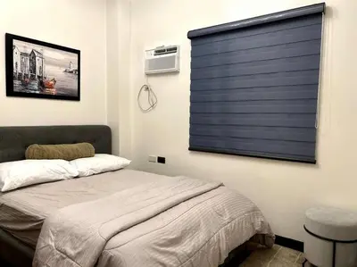 a bedroom with a bed with a blue blind on the window at Kapitolyo Prisma Residential Condo TCPH21 - NYC Vibes Penthouse with KTV Pool and Balcony with City View Panorama 5 Min Drive to BGC St Lukes and Ortigas - Staycations by SMS in Manila