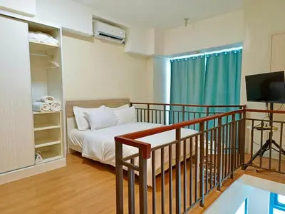 a bedroom with a bed and a balcony with a television at Best Value Stylish Loft Steps from Greenbelt Mall in Manila