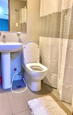 a bathroom with a toilet and a sink and a shower at Best Value Stylish Loft Steps from Greenbelt Mall in Manila
