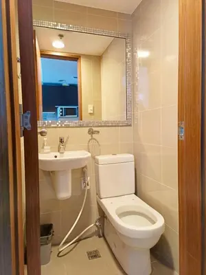 a bathroom with a toilet and a sink and a mirror at Best Value Stylish Loft Steps from Greenbelt Mall in Manila