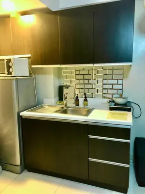 a kitchen with a sink and a refrigerator at Best Value Stylish Loft Steps from Greenbelt Mall in Manila