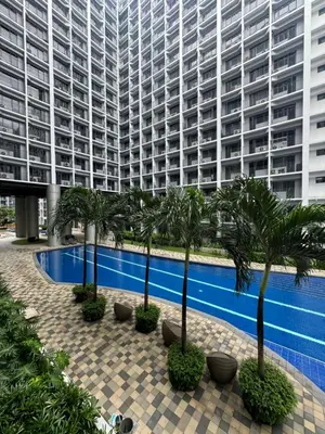 a large apartment building with a swimming pool and palm trees at Cozy Korean Studio Shore 2 Residences in Manila