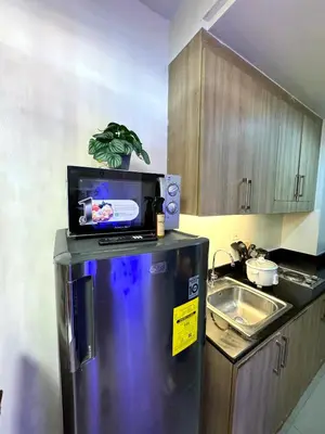 a kitchen with a refrigerator with a microwave on top of it at Cozy Korean Studio Shore 2 Residences in Manila