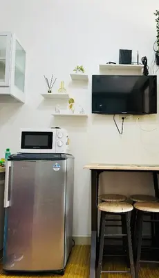 a kitchen with a refrigerator and a table with stools at LD Cozy Condo - Grace Residences, Taguig City near BGC in Manila