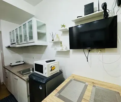 a kitchen with a microwave and a tv on the wall at LD Cozy Condo - Grace Residences, Taguig City near BGC in Manila