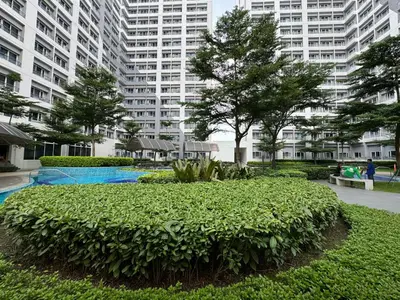 a park with a bush in front of a large building at LD Cozy Condo - Grace Residences, Taguig City near BGC in Manila