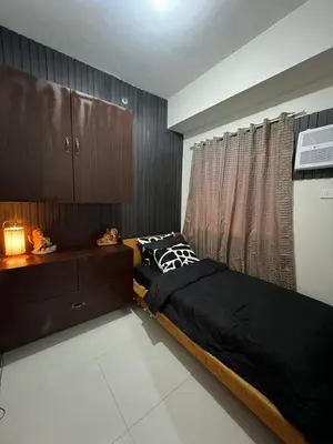 a bedroom with a black bed and a window at Trina's Suites in Manila