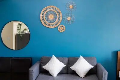 a blue living room with a couch and a mirror at LUXX BGC Venice in Manila