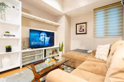 a living room with a couch and a tv at Avant at the Fort BGC 1BR Flr to Ceiling Cor Unit with Great View in Manila