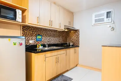 a kitchen with wooden cabinets and a sink and a refrigerator at Avant at the Fort BGC 1BR Flr to Ceiling Cor Unit with Great View in Manila