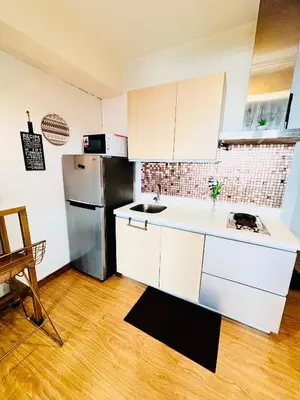 a kitchen with white cabinets and a stainless steel refrigerator at Azure Staycation by Via Sabby in Manila