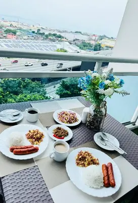 a table with plates of food on a balcony at Azure Staycation by Via Sabby in Manila