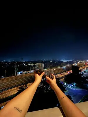 two people holding up wine glasses on a balcony at Azure Staycation by Via Sabby in Manila