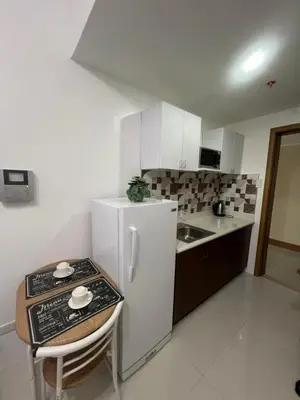 a kitchen with a white refrigerator and a table at Condo In front of US Embassy Studio Unit with 2 Double Beds in Manila