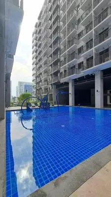 a large blue swimming pool in front of a building at Cozy Condo Stay Near MOA in Manila