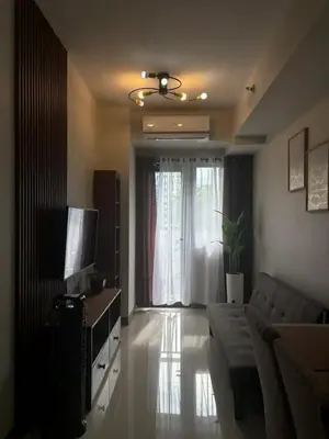 a living room with a couch and a television at Cozy Condo Stay Near MOA in Manila