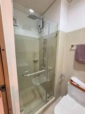a bathroom with a glass shower with a toilet at Design And Den - LK Urban Suites in Manila