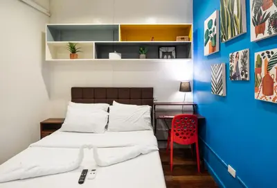 a bedroom with a bed and a desk and a red chair at Homey and Cozey Poblacion Makati S11 in Manila